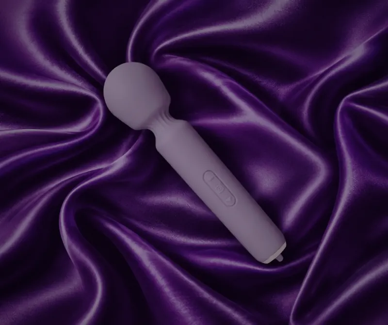 Lilac massage wand resting on purple satin